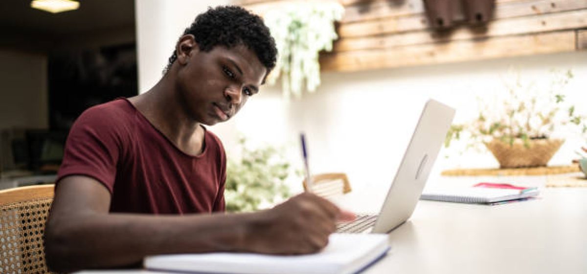 Teenager boy studying with laptop at home