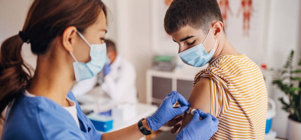 Nurse putting band aid on patient's arm after covid-19 vaccination
