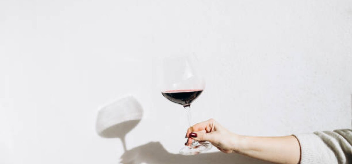 Women's hand holding a glass of red wine.