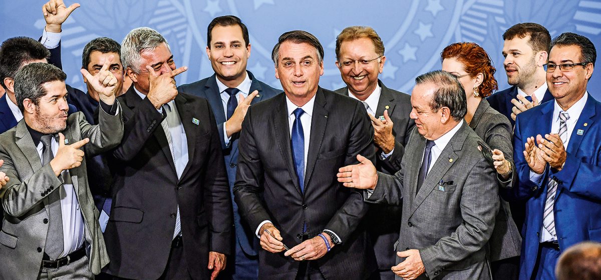 Brazilian President Jair Bolsonaro (C) is pictured surrounded by parliamentarians during the signing ceremony of the decree that facilitates to own, carry and import weapons, at the Planalto Palace in Brasilia, on May 7, 2019. (Photo by EVARISTO SA / AFP)